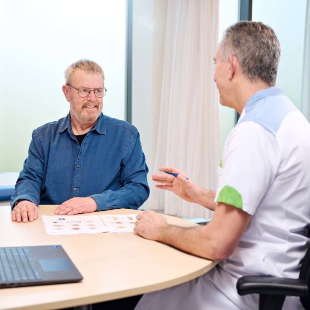 Dokter en patiënt zitten samen aan tafel en spreken met elkaar Centrum voor leefstijlgeneeskunde Hans van Kuijk