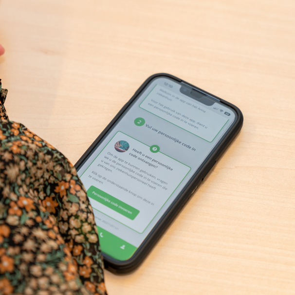 Een mobiele telefoon met op het scherm de Patient Journey App Patient Journey App