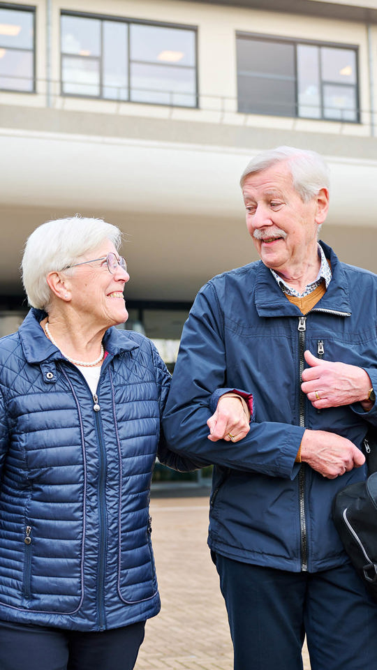 Echtpaar loopt gearmd met tas voor Anna Ziekenhuis Persoonlijke en goede zorg Anna Ziekenhuis