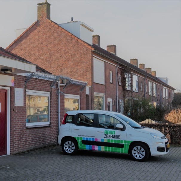 Voorzijde gebouw bloedafnamelocatie Gezondheidscentrum Gestel Midden in Eindhoven. Met geparkeerde auto met logo Anna Ziekenhuis. Bij het Anna Ziekenhuis kun je op meerdere locaties in de regio bloed laten afnemen en lichaamsmateriaal zoals urine en ontlasting inleveren.