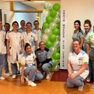 Team zorgverleners staat bij de ingang van het Vrouw Moeder Kind Centrum Team zorgverleners viert de nieuwe naam van het Vrouw Moeder Kind Centrum